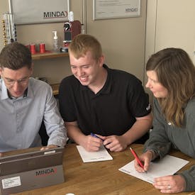 Ausbildung Eine Gruppe von 4 Mitarbeitern von MINDA sitzt an einem Schreibtisch