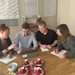 Eine Gruppe von 4 Mitarbeitern von MINDA sitzt an einem Schreibtisch