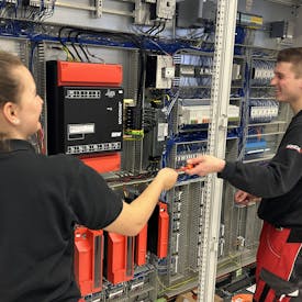 Ausbildung Zwei junge Arbeiter von MINDA stehen vor einem Schaltschrank