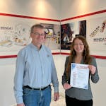 Eine MINDA Auszubildende bekommt eine Urkunde überreicht