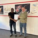 Ein Azubi von MINDA wird mit einer Urkunde ausgezeichnet