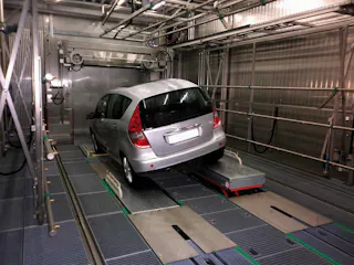 Leak test A car stands at a slight angle on a conveyor belt in a production plant