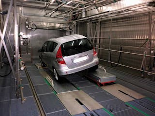 Leak test A car stands at a slight angle on a conveyor belt in a production plant