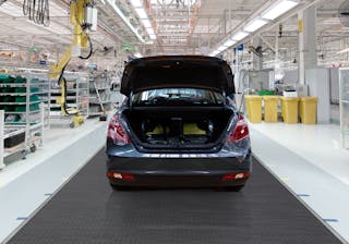 Work conveyors A car with an open boot is parked in a production plant